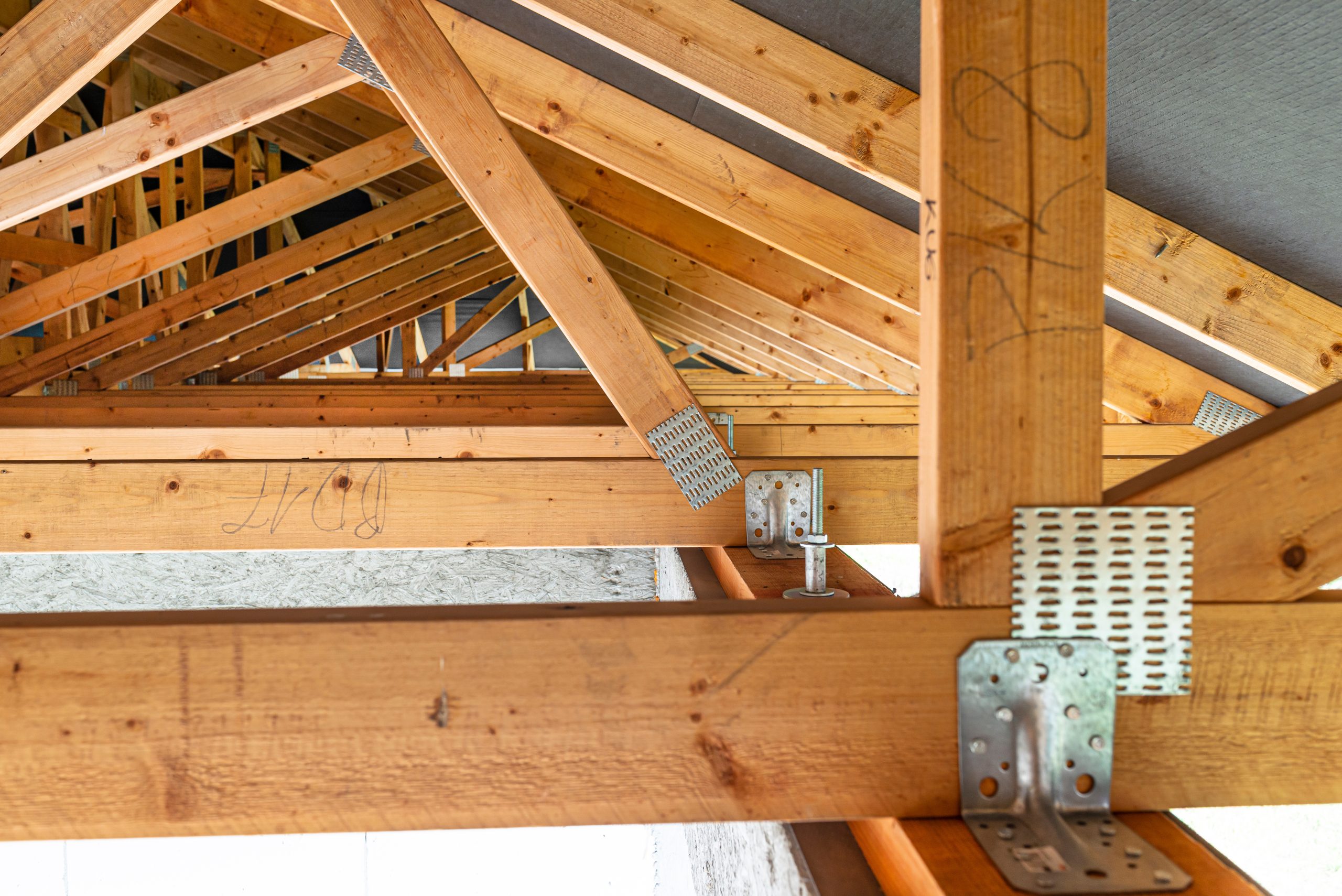 Roof trusses covered with a membrane on a detached house under construction, view from the inside, visible roof elements and truss plates.
